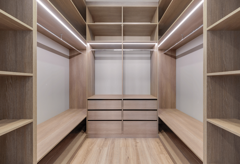 Vestidor a medida con madera clara y estantes iluminados