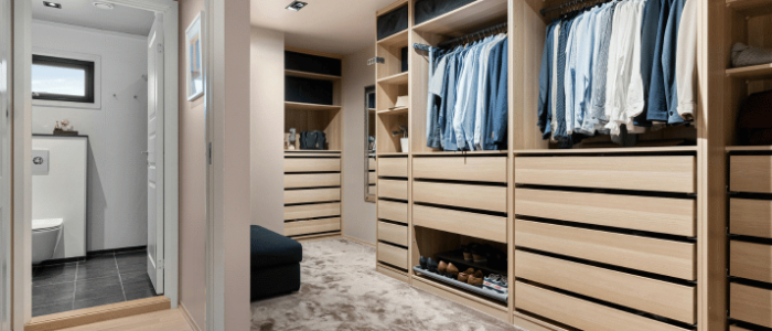 Vestidor a medida con estanterías de madera clara y iluminación empotrada
